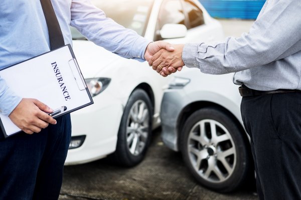 Shaking hands in front of car accident.