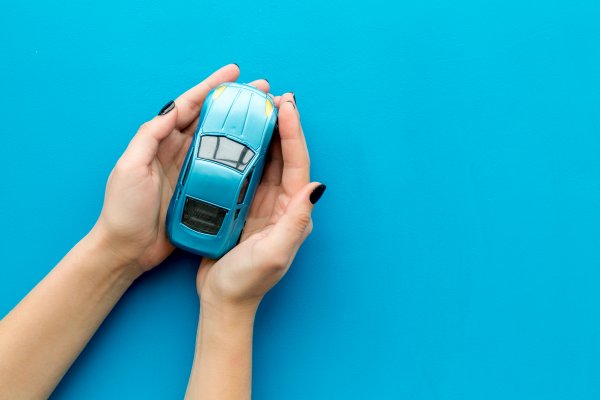 Small toy car in hands on a blue background