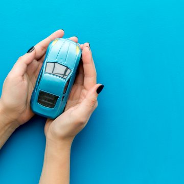Small toy car in hands on a blue background