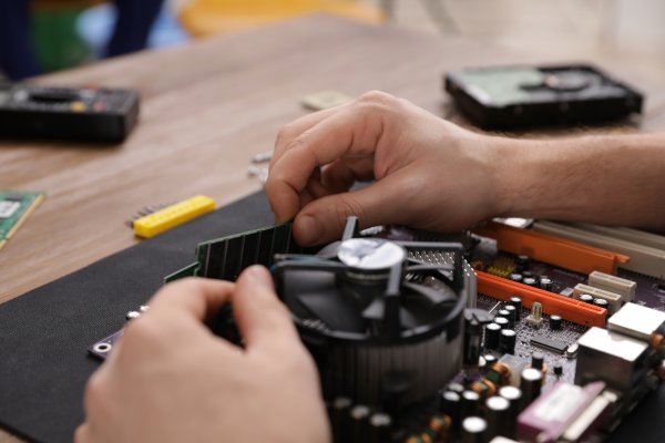 A computer users hands trying to fix a broken piece of their computer.