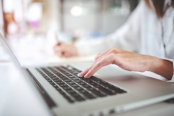 Computer with users hand on top of laptop.