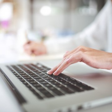 Computer with users hand on top of laptop.