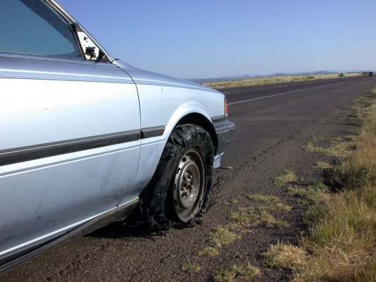 Broken down blue car that wishes it has USAA extended warranty service, because it is stuck on the side of the road. 