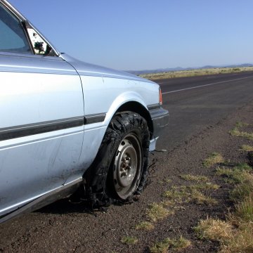 Broken down blue car that wishes it has USAA extended warranty service, because it is stuck on the side of the road. 