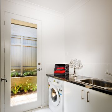 Washing machine in the corner of a room under some cabinets 