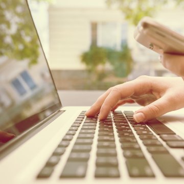 purevpn vpn services google chrome hand typing on laptop holdin smartphone