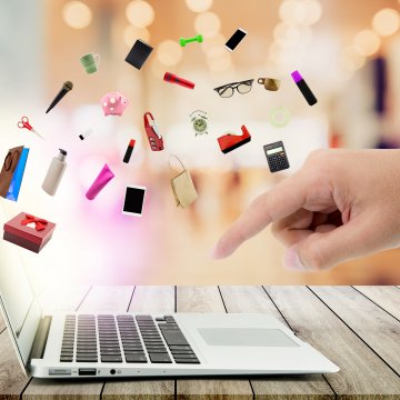 ecommerce shopping cart ashop online shopping products coming out of laptop hand pointing at laptop keyboard