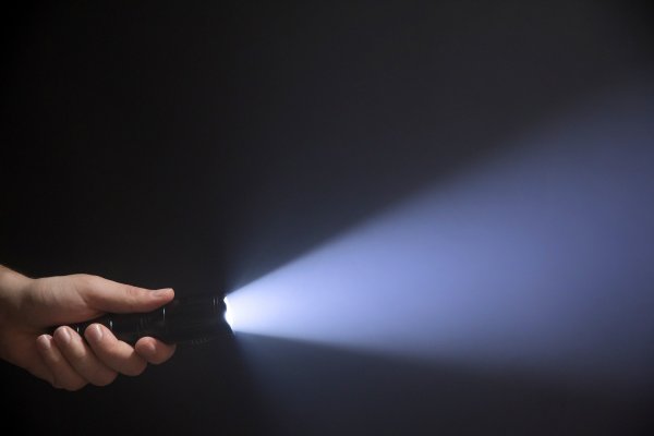 holding a turned on flashlight beam of light 