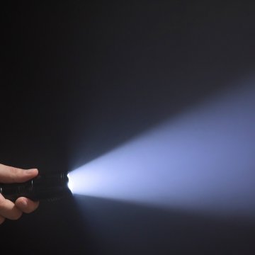 holding a turned on flashlight beam of light 