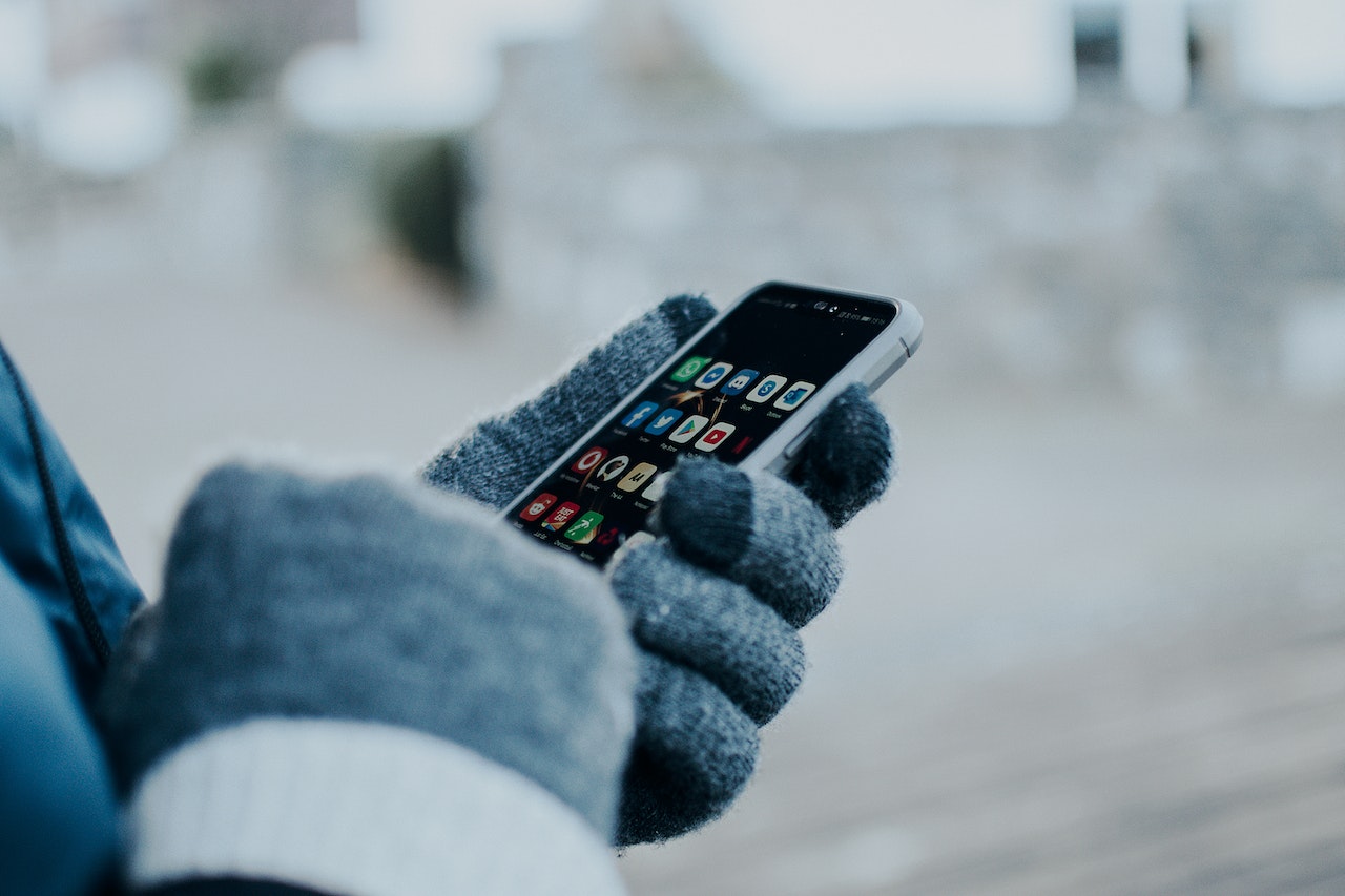 person with gloves on using an app on a cell phone