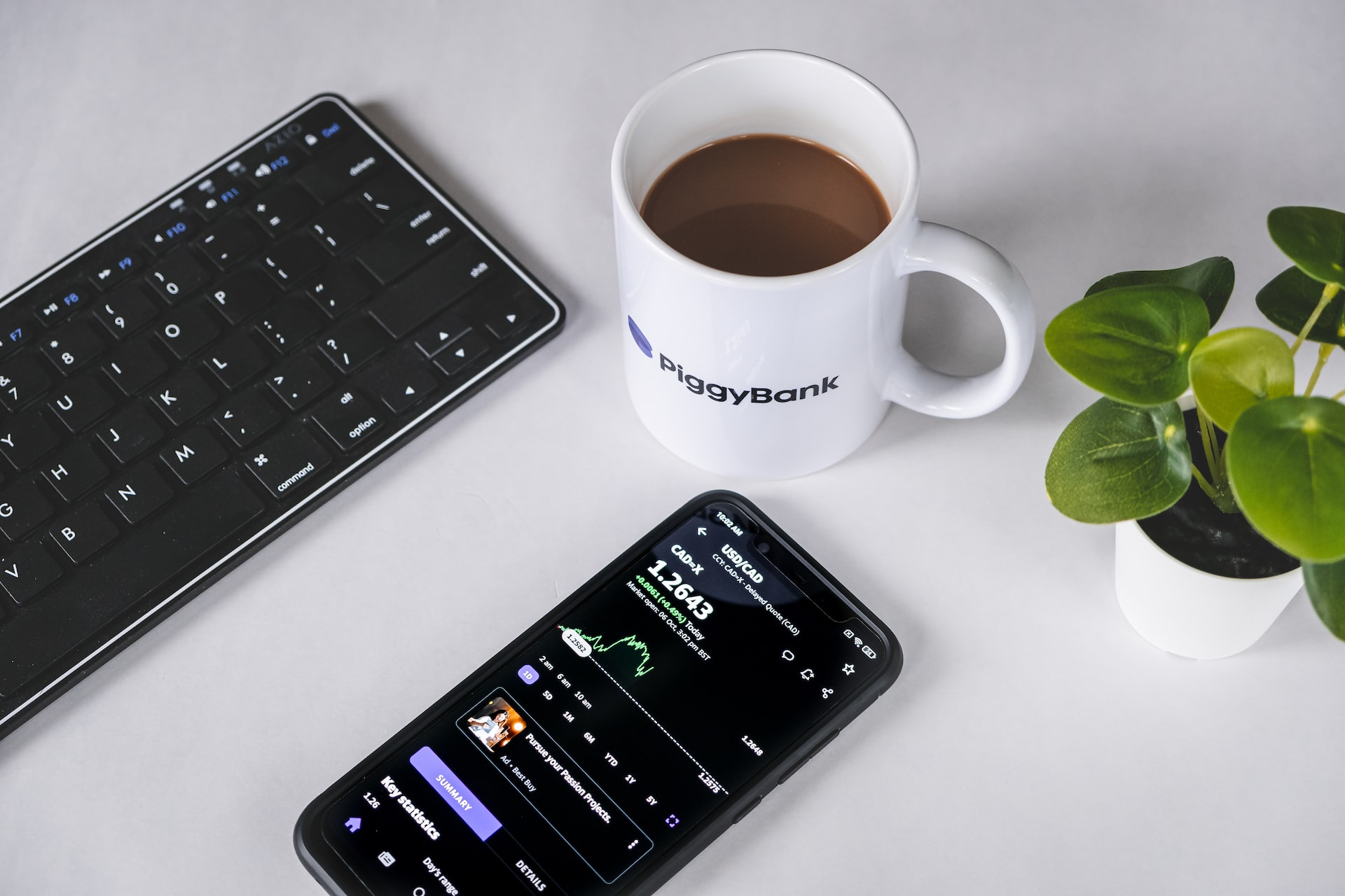 banking app on a phone, beside a keyboard and cup of coffee