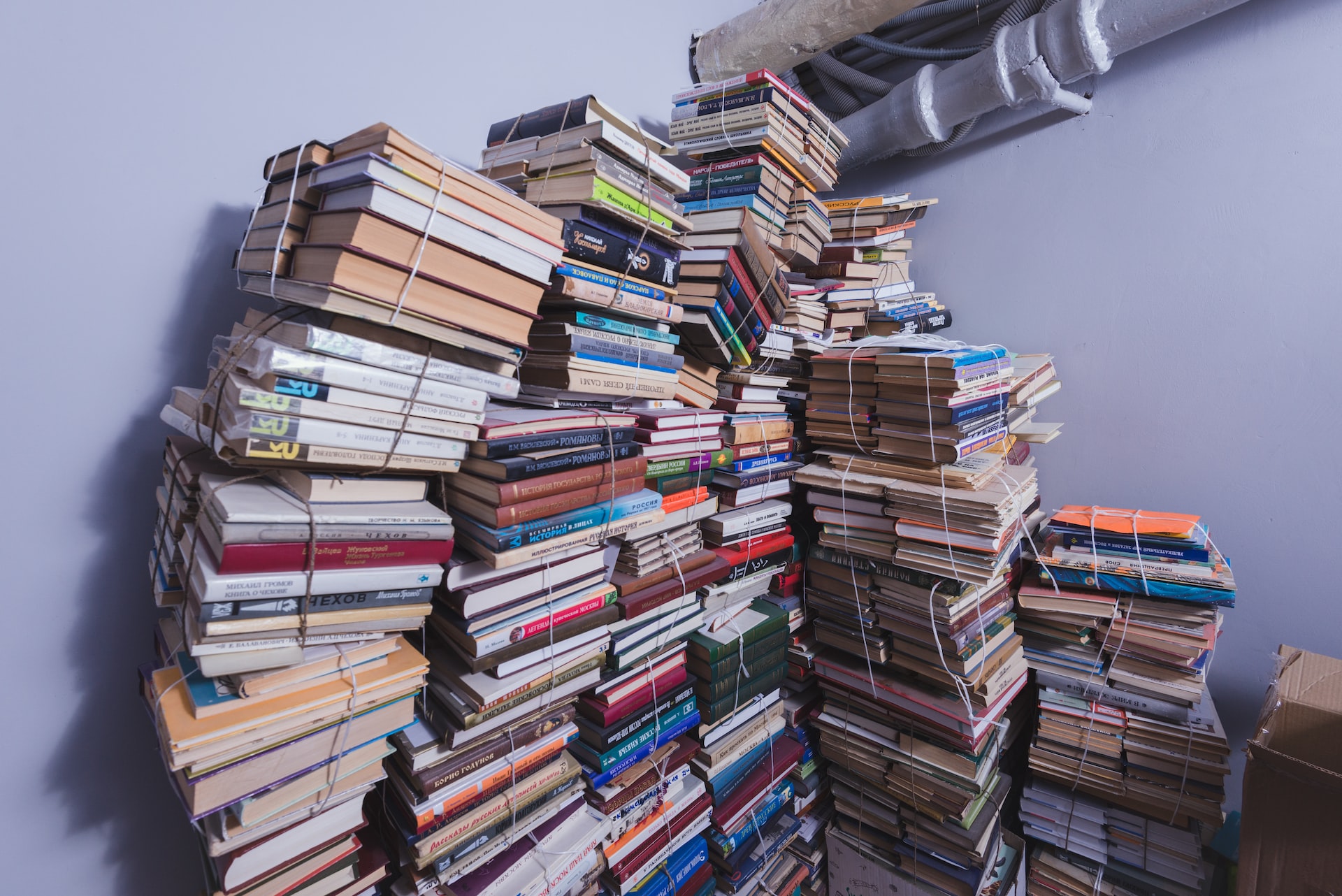 leaning pile of books about to fall over in the corner of a room