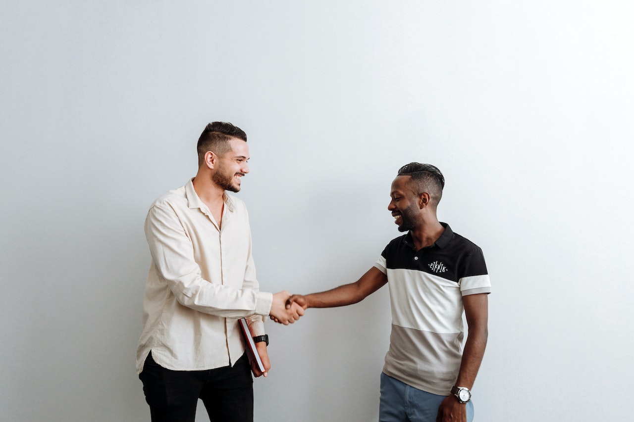 two people shaking hands in front of a white background