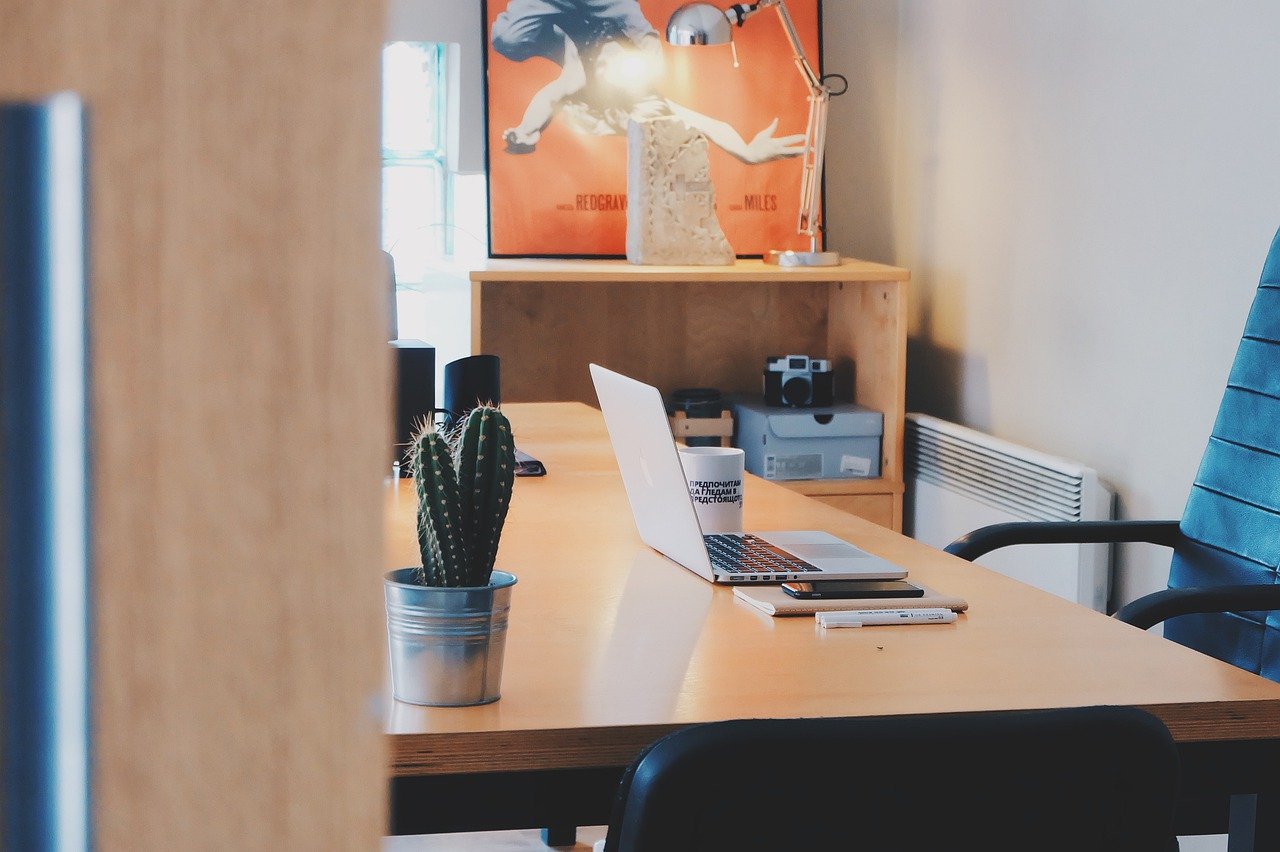 an empty office with a laptop on the desk open