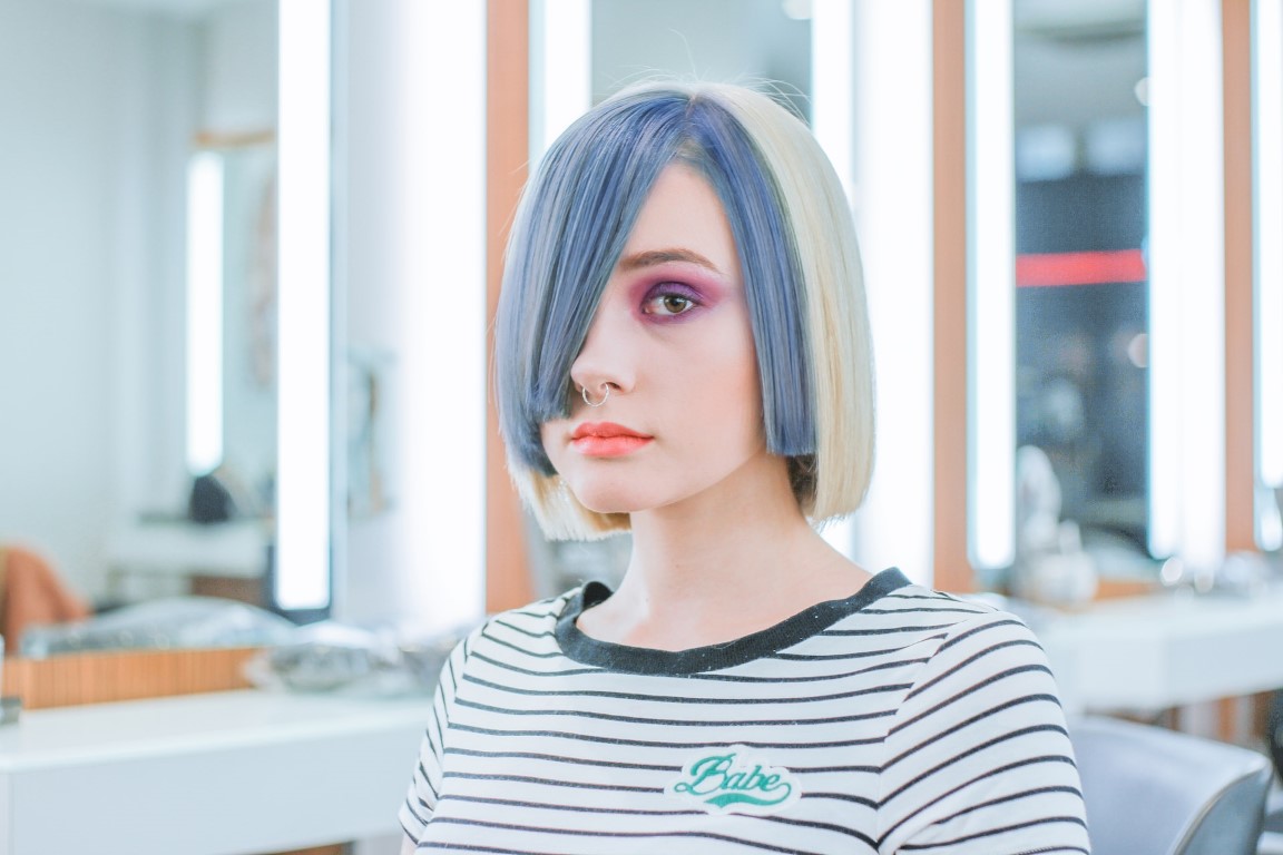 a person with blue streaked blonde hair sitting down