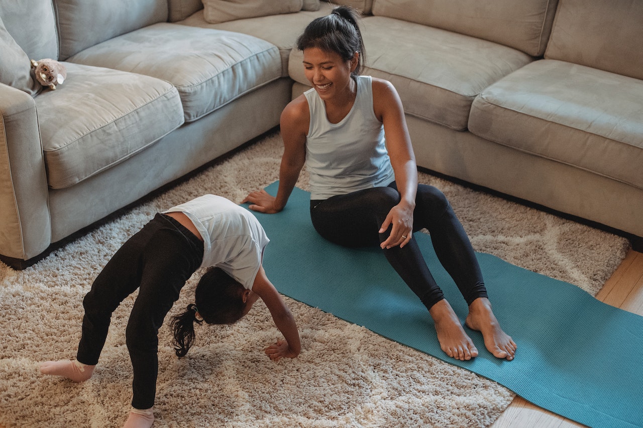 adult and child stretching in their living room on a yoga mat