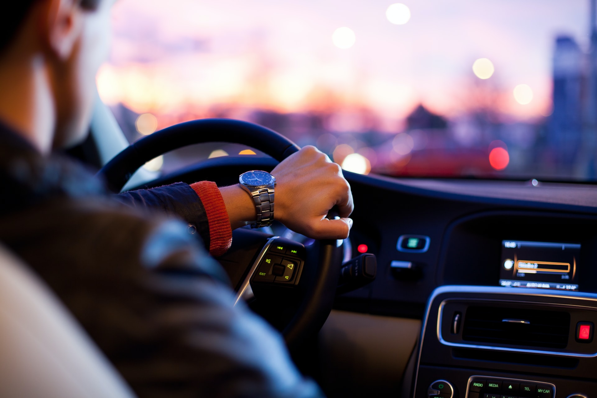 a person driving a nice car with a city scape in the background