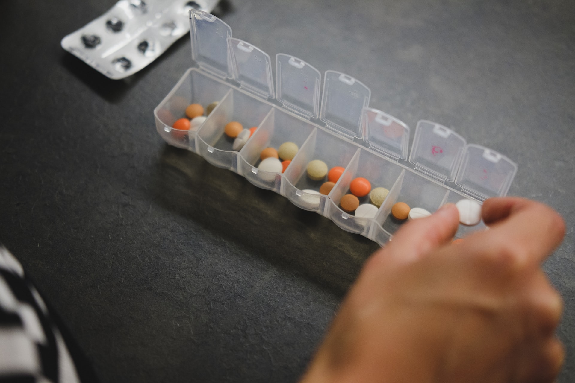 person putting pills in organizer 