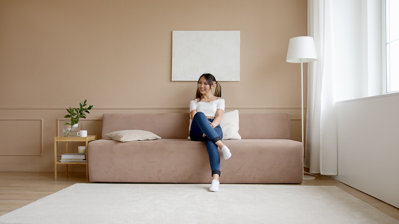 person sitting on a beige couch in a well lit room