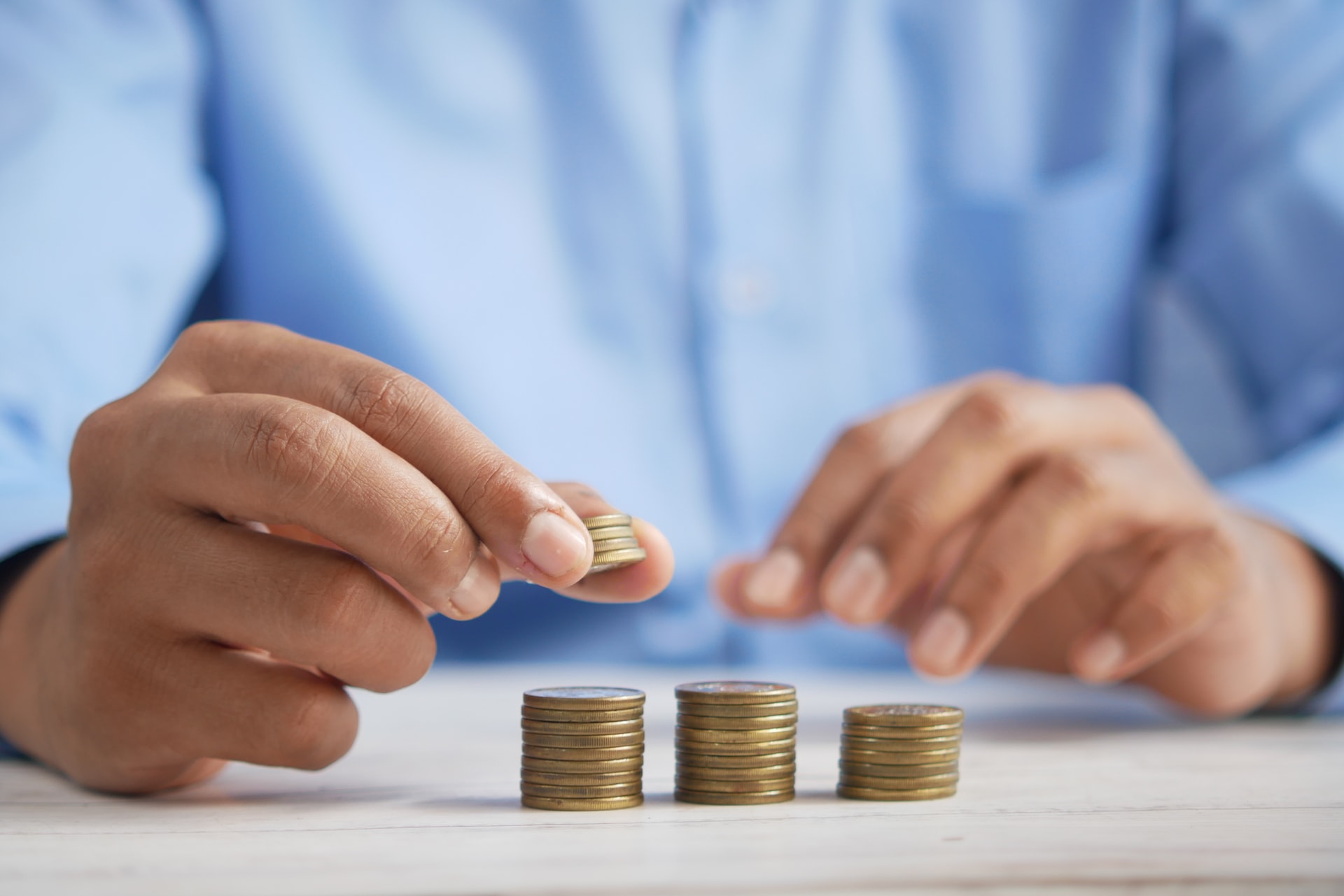 person with a blue shirt on stacking up some coins