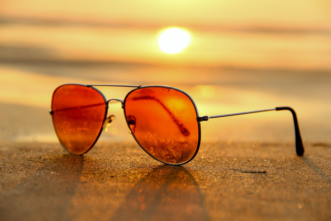 amber sunglasses on a beach with a sunset in the background