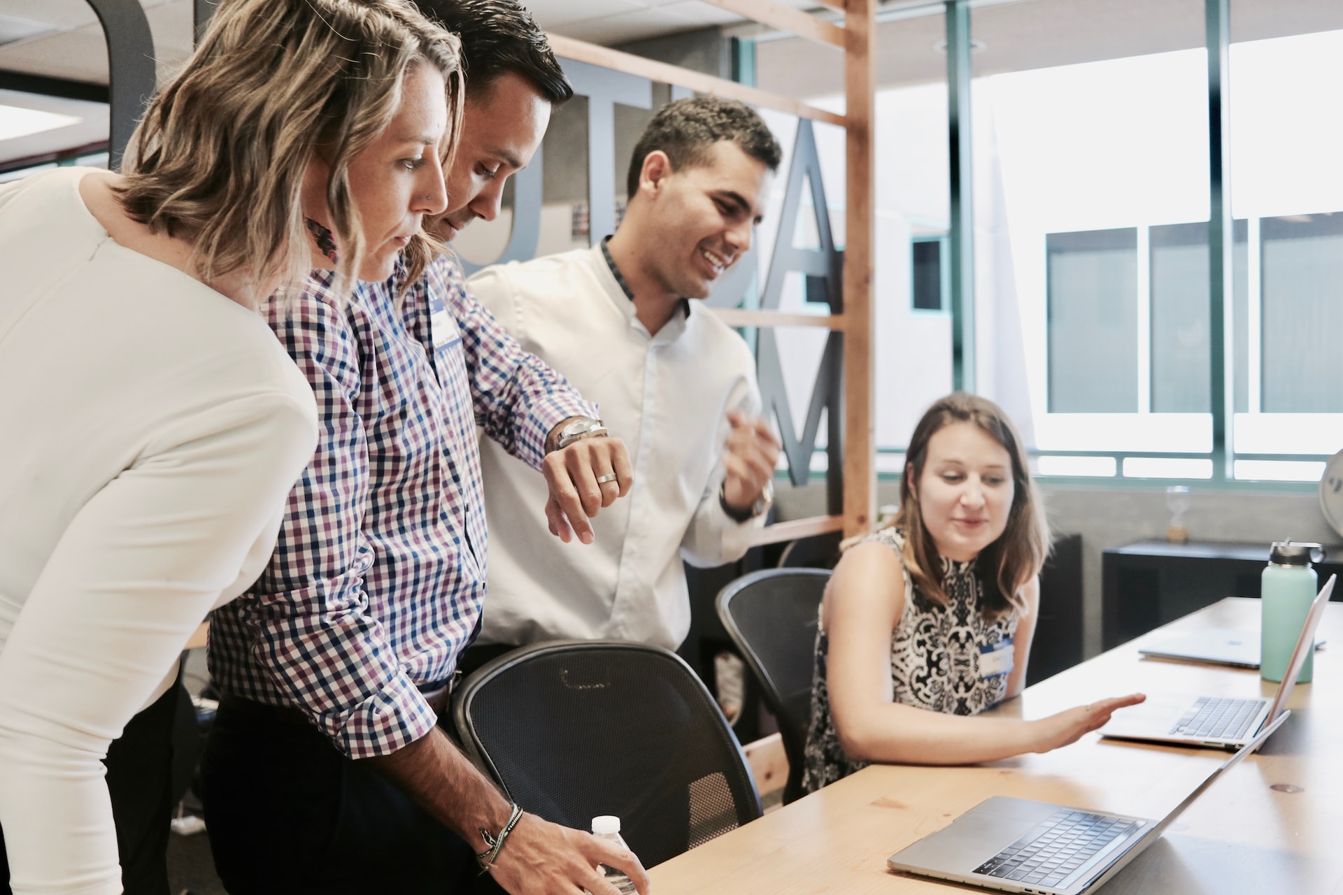 people standing around a person on a laptop