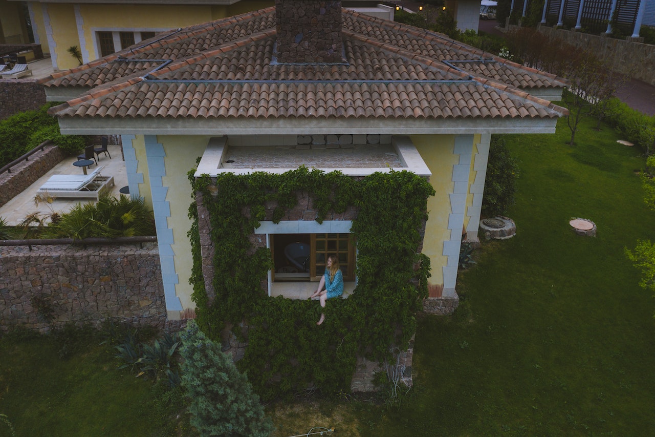 a sitting area on the backside of a house with green vines growing around it