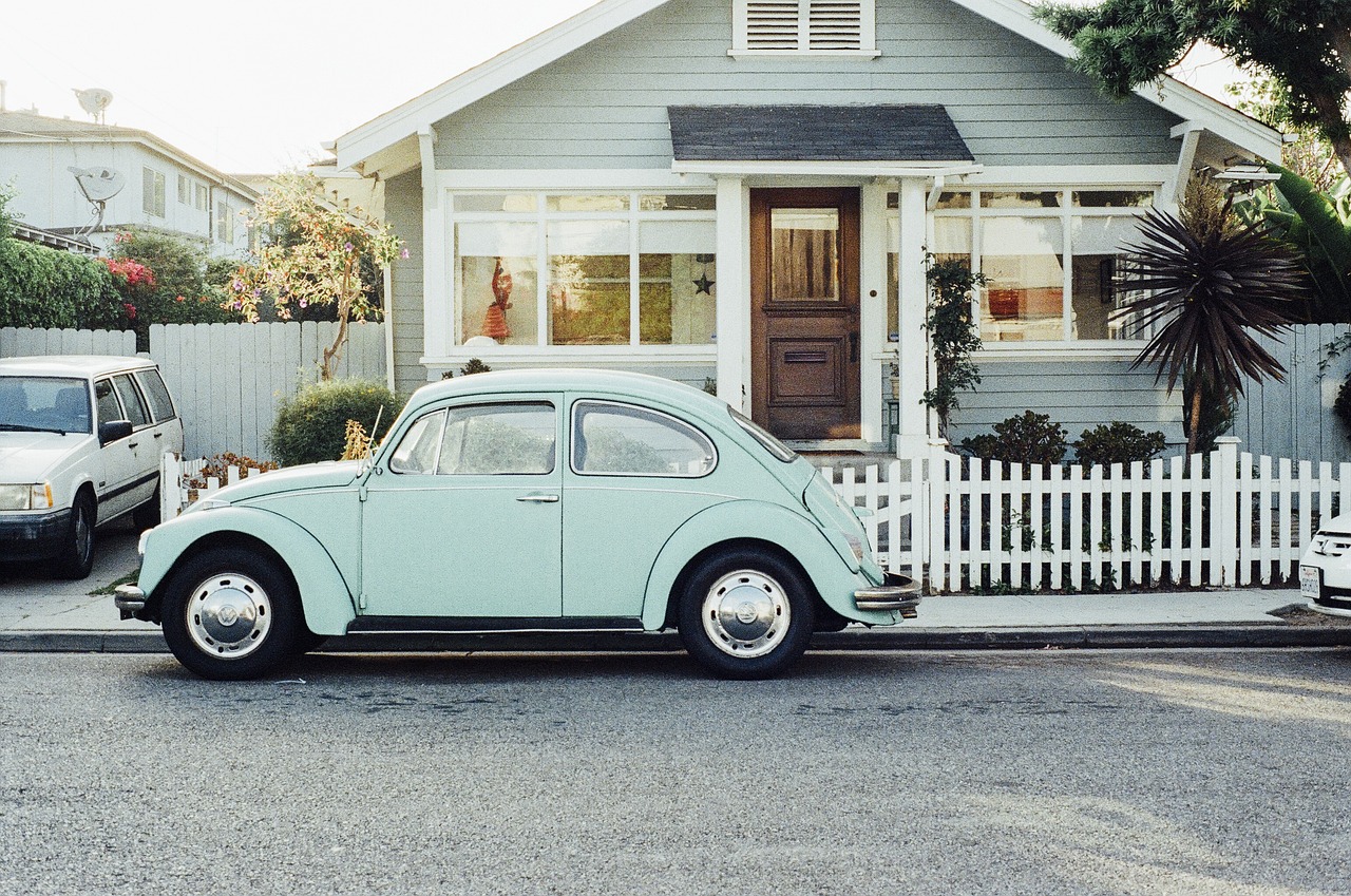 light colored VW beetle parked in front of a house 