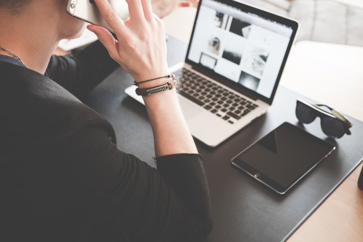 man talking on smartphone in front of laptop, project management, clarizen