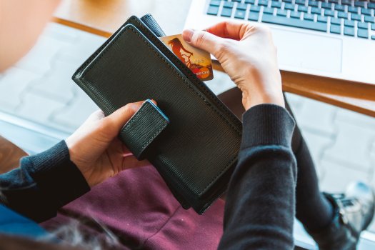 woman searching for credit card in wallet in front of laptop, ecommerce, big commerce